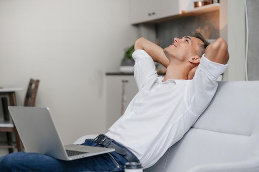 close up. dreaming young man with a laptop sitting on the couch.