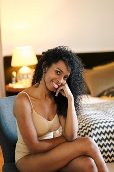 Young afro american woman wearing underwear and sitting in bedroom. Concept of relax and beauty.