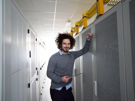 Male IT engineer working on a tablet computer in server room at modern data center