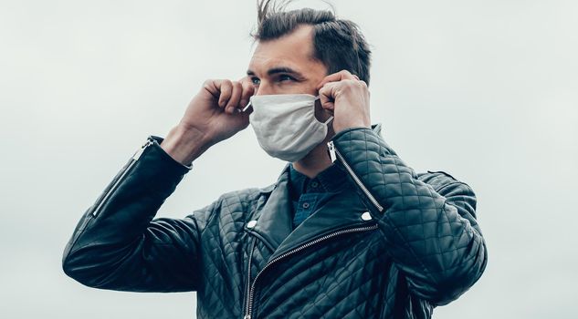 young man putting on a protective mask standing on the street. photo with a copy-space