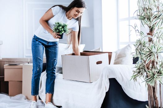 happy young woman takes things out of cardboard boxes. moving to a new apartment