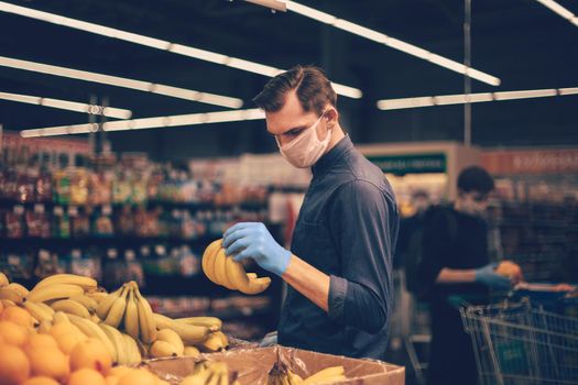 man in protective gloves choosing bananas in a supermarket. hygiene and health care
