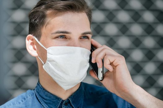 close up. attractive young man in a protective mask talking on a smartphone. coronavirus in the city