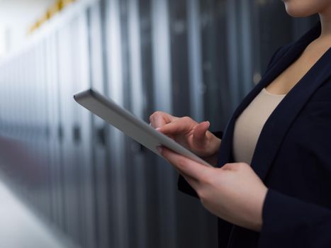 Female IT engineer working on a tablet computer in server room at modern data center