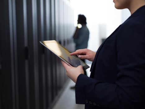 Female IT engineer working on a tablet computer in server room at modern data center