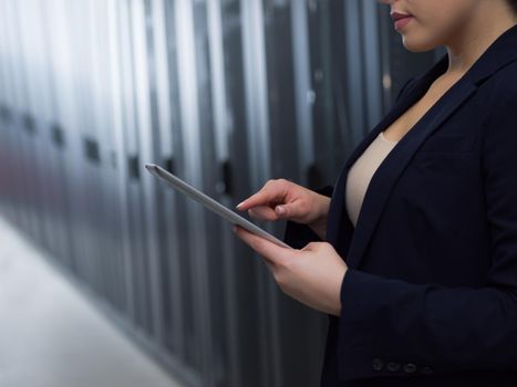 Female IT engineer working on a tablet computer in server room at modern data center