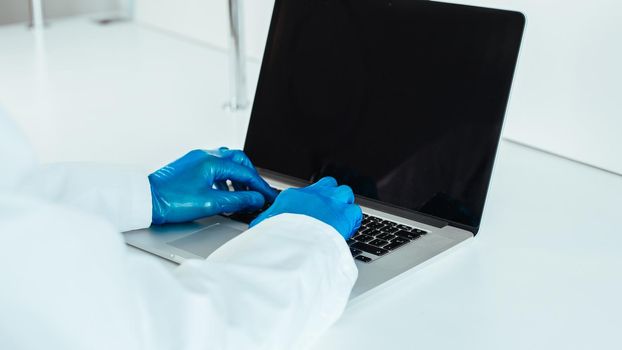 close up. doctor in protective gloves typing on a laptop . the concept of telemedicine.