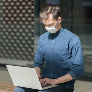 close up. city guy in a protective mask is working on a laptop. concept of health protection.