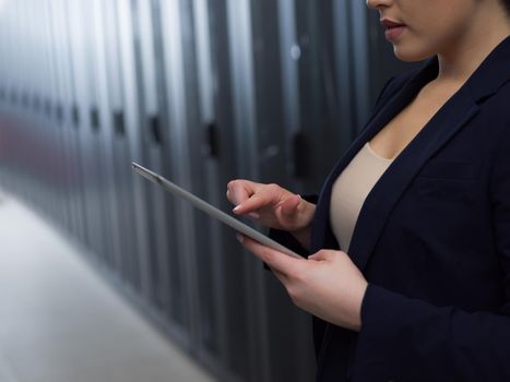 Female IT engineer working on a tablet computer in server room at modern data center