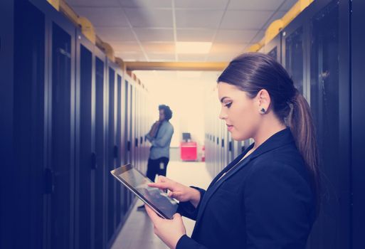 Female IT engineer working on a tablet computer in server room at modern data center