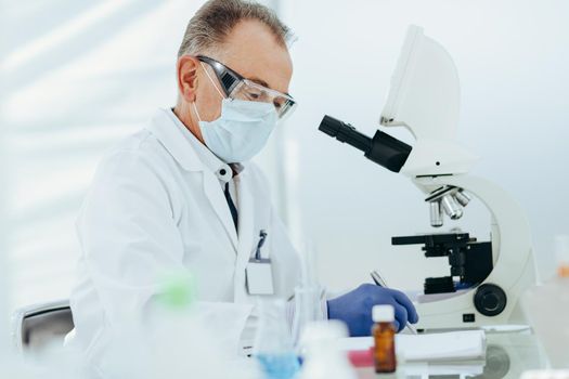 close up. scientist in a protective mask conducts research in the laboratory. photo with a copy-space.