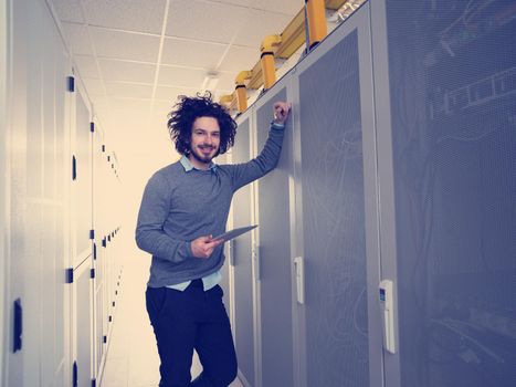 Male IT engineer working on a tablet computer in server room at modern data center