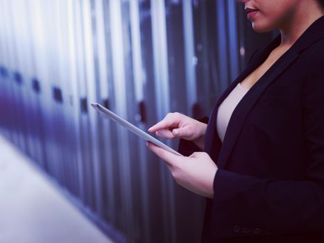 Female IT engineer working on a tablet computer in server room at modern data center