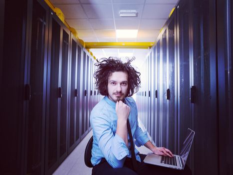 Male IT engineer working on a laptop in server room at modern data center