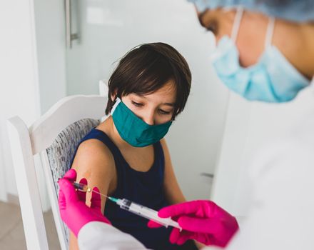 Little cute child with mask getting injection