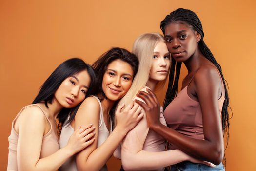 young pretty asian, caucasian, african woman posing cheerful together on brown background, lifestyle diverse nationality people concept close up