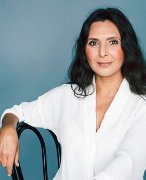 pretty brunette confident mature woman sitting on chair in studio, lifestyle people concept close up