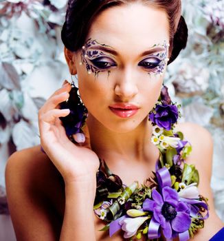 floral face art with anemone in jewelry, sensual young brunette woman in studio close up, 8 march concept