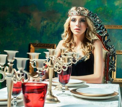 young blond woman wearing crown in fairy luxury interior with empty antique frames total wealth concept close up