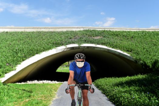Cyclist on a bike path wearing a COVID-19 surgical mask.