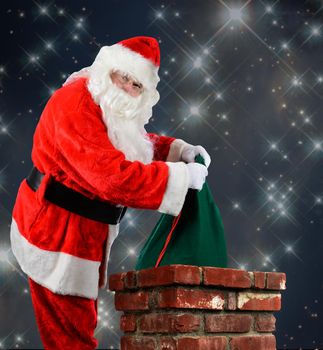 Closeup of Santa Claus placing his bag of toys into a chimney. Vertical format over a starry night time background.