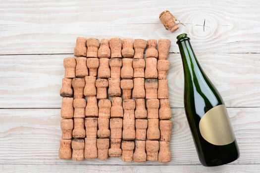 HIgh angle shot of a empty champagne bottle with blank label and corks. Closeup on a rustic white wood table. Horizontal format with copy space.