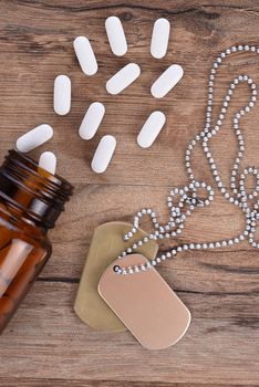 Military and Veterans Health Care Concept. Dog tags and pills on a wood background.