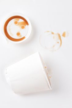 Top view of a crushed paper coffee cup with lid and coffee stains.