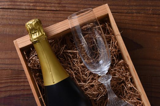 A bottle of Champagne in a wood gift box with a crystal flute. 
