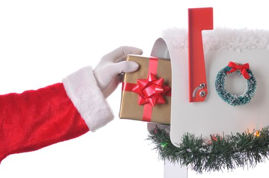 Santa Claus Placing wrapped present in mailbox that is decorated for Christmas with wreath, garland and snow