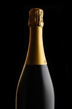 Closeup of an unopened bottle of Champagne against a black background. 