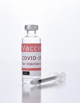 Closeup of a Covid-19 Vaccine vial and syringe on white.