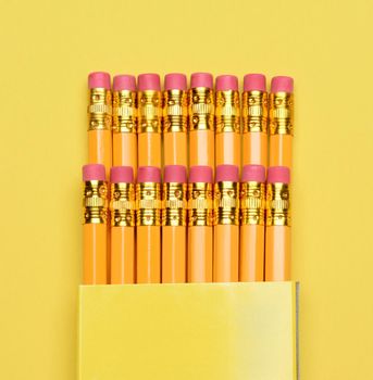 Closeup of a box of new pencils on a yellow background.