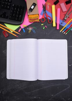 School Supplies: Still life on erased Chalkboard with open notebook and copy space.