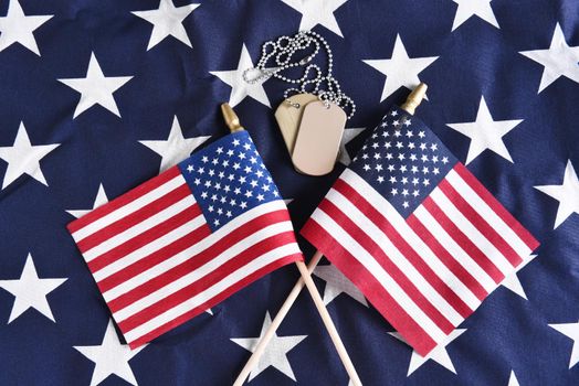 Top view of two crossed American Flags on the star field of a large flag with military dog tags. Perfect for Veterans Day, Memorial Day or other patriotic projects.
