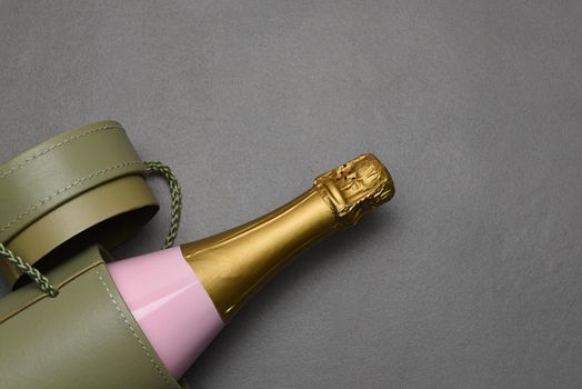 Champagne bottle in gift box laying on a gray slate surface wtih copy space.