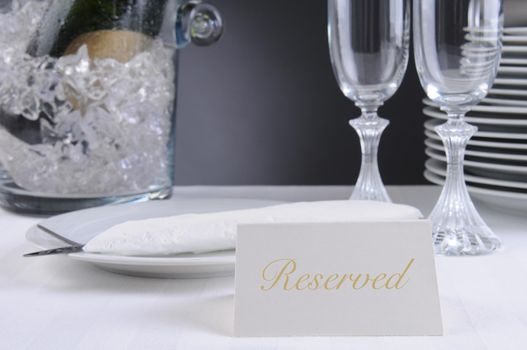 Closeup of a Reserved sign on a restaurant table that is set for an elegant occasion. Shallow depth of field.