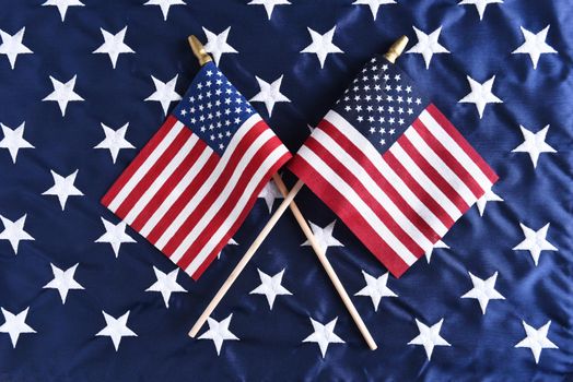 Two small American flags crossed on the star field of a larger flag. Perfect for Fourth of July or other patriotic American holidays.