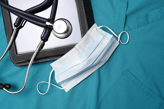 Stethoscope, surgical mask and medical tablet computer on a set of surgical greens, Scrubs. 