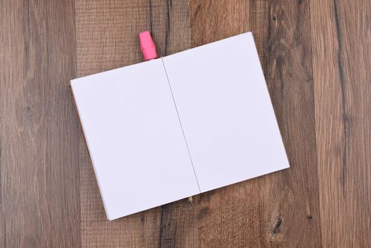 Open writing pad with a pencil underneath. High angle shot on a wood background. The pads pages are blank.