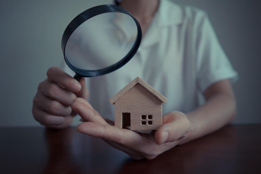 Concepts of home search for housing or home appraisal. Business Woman or bank officer using a magnifying glass to checking the model house.