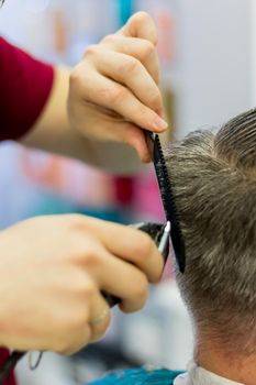 The hairdresser cuts the man's hair with a clipper and comb. Short men's haircut. Close-up.