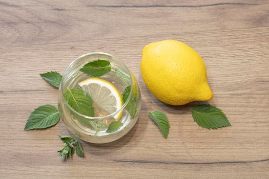 Whole lemon and lemon water with mint and mint leaves on the table