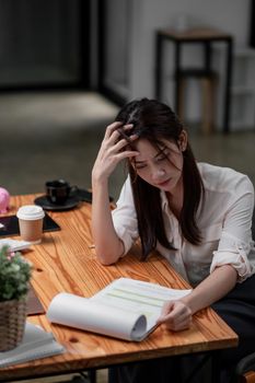 Stressed asian business woman working with marketing report. business financial concept