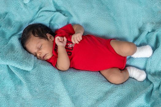 Infant asleep lying on his stomach, dressed in red clothes