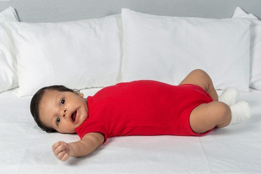 Infant child lying on his back. Wearing red clothes