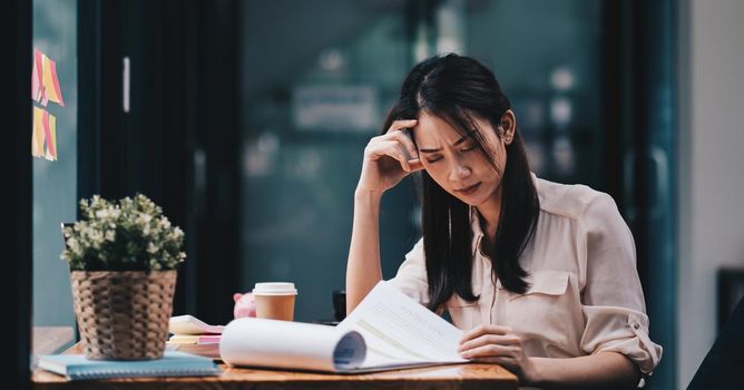 Tired young asian woman feel headache from working problem. Stressed female suffer from headache bad vision sight problem sit at workplace