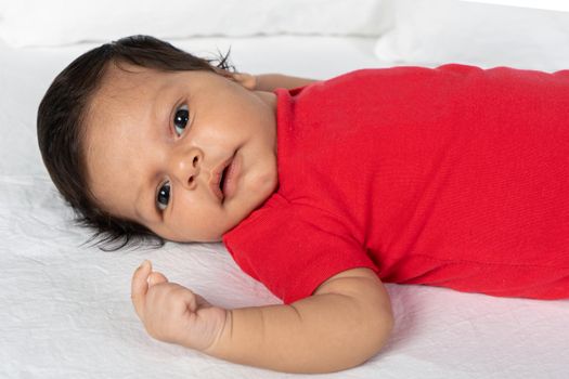 Infant child lying on his back. Wearing red clothes