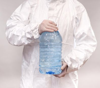 a man holds a large full plastic transparent bottle with water liquid. an employee in a protective suit and gloves in the laboratory. the concept of poor ecology and pollution of drinking water. on a white background