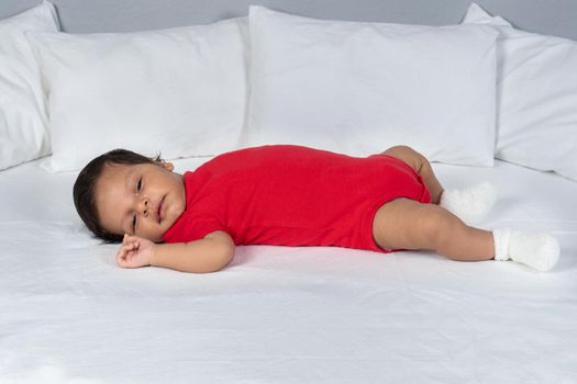 Infant child lying on his back. Wearing red clothes